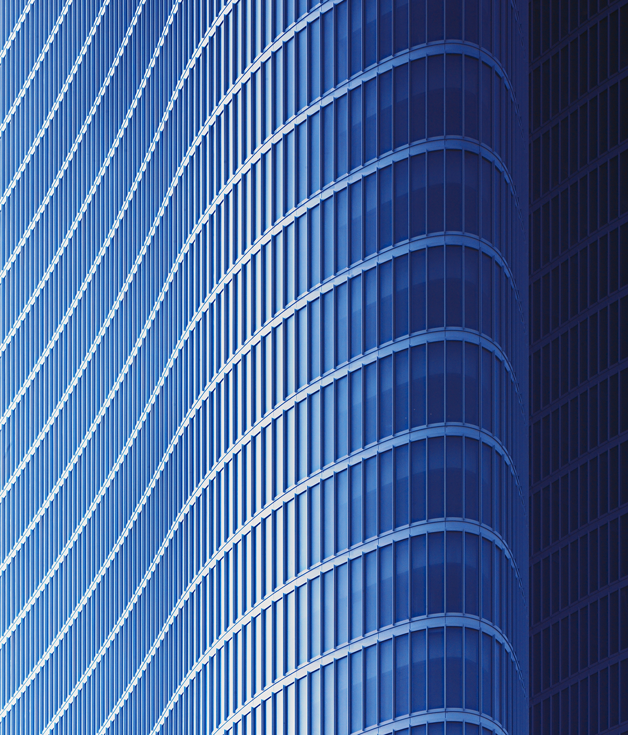 Closeup photo of a curved, glass office building facade.